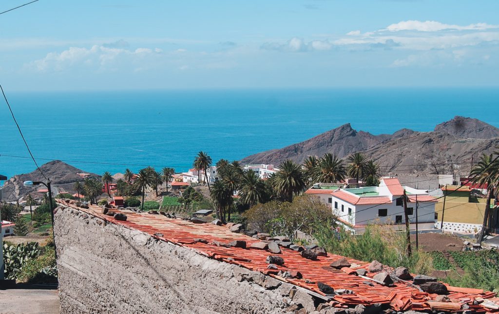 View over the village with palm trees, houses and the blue ocean.